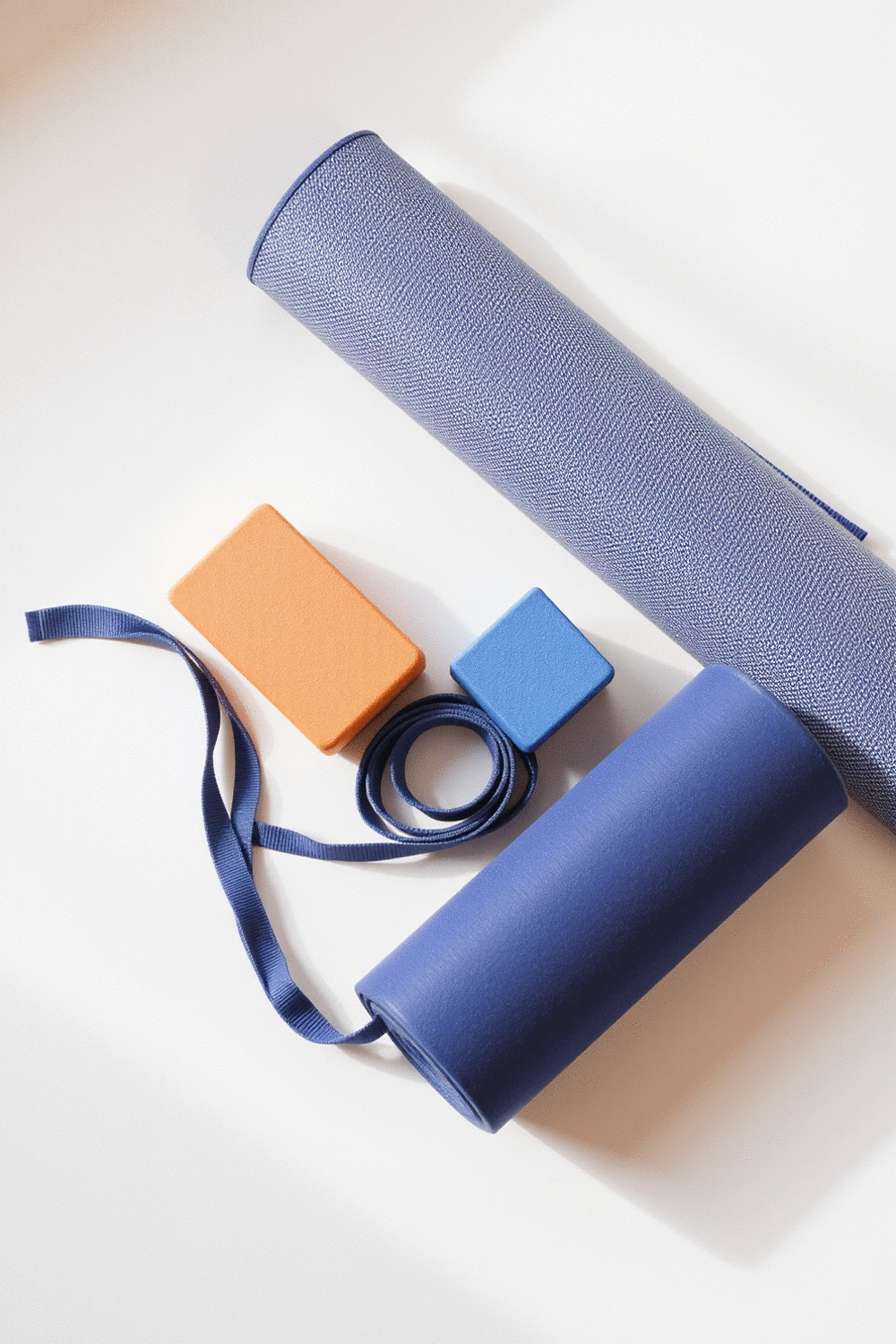 Yoga props: mat, blocks, strap, and bolster neatly arranged in a calm studio setting