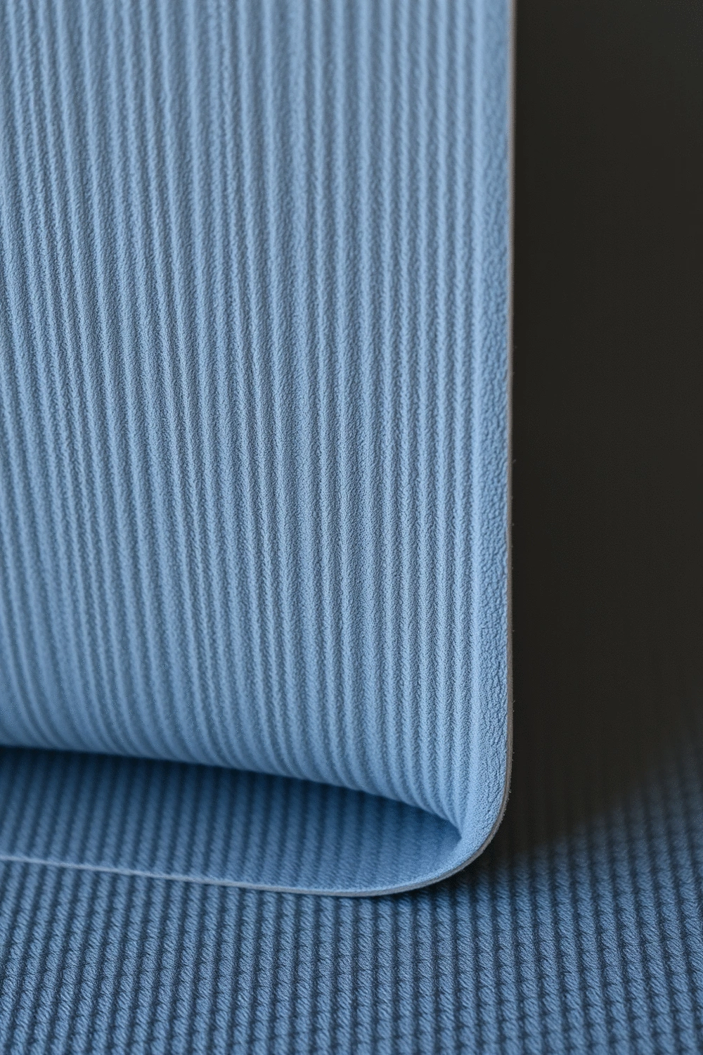Close-up of a natural rubber yoga mat, showing its texture and grip, with soft, diffused lighting.
